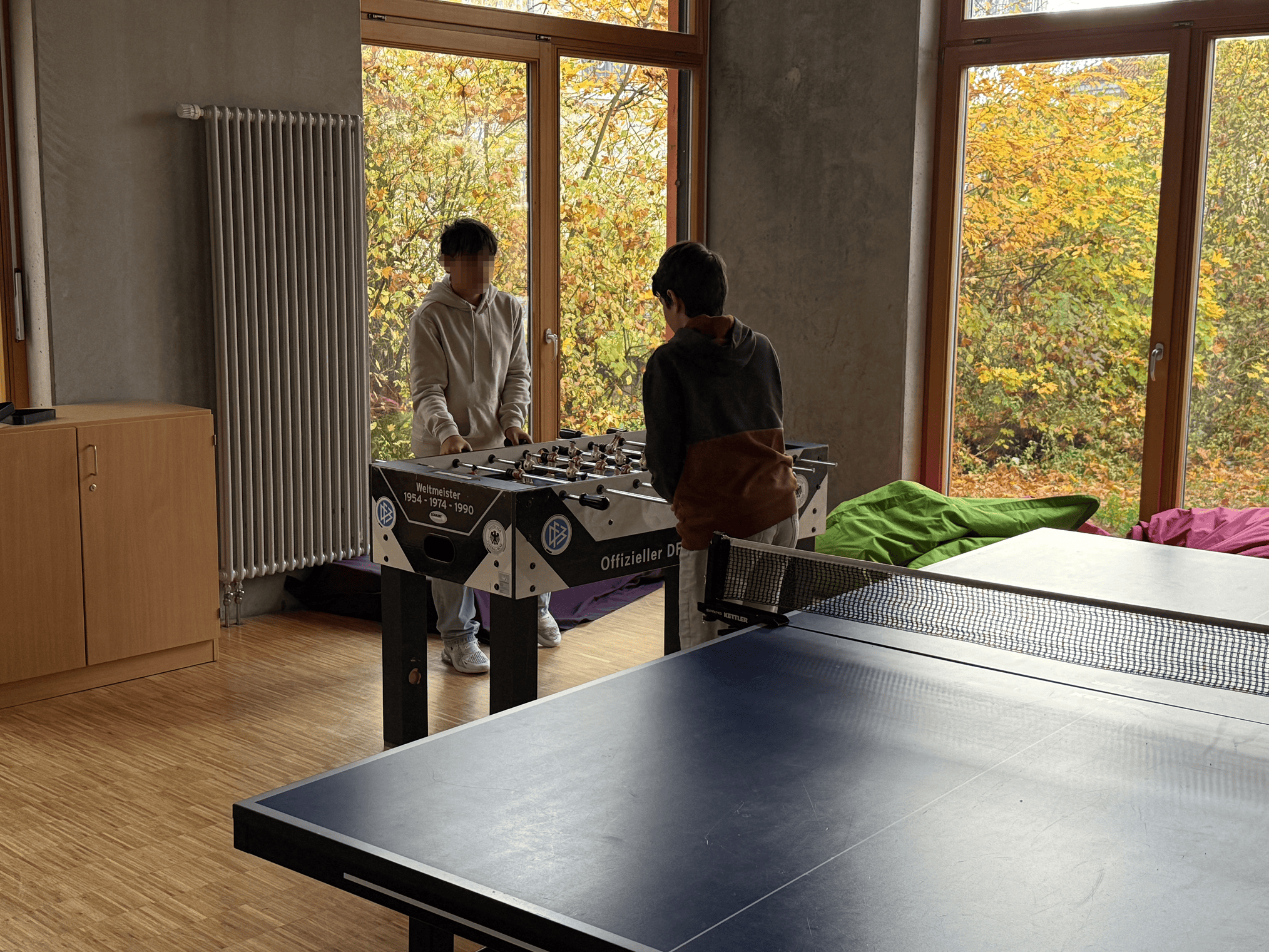 Zwei Jugendliche spielen Tischkicker.