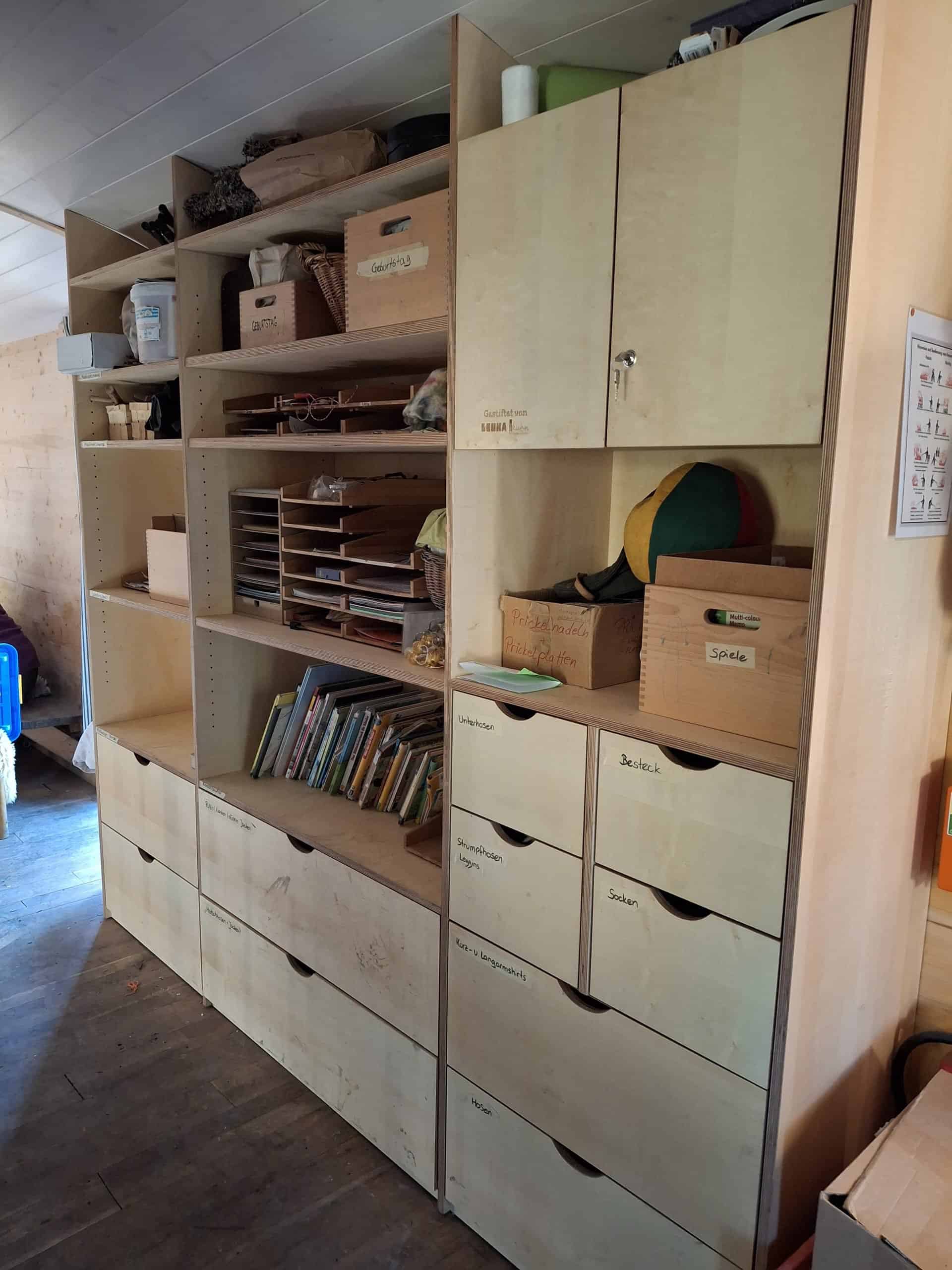 Ein Holzregal mit verschiedenen Schubladen und Fächern im Bauwagen des Waldkindergarten Weiler.
