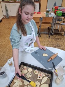 Eine Schülerin bepinselt Osterplätzchen auf einem Blech.