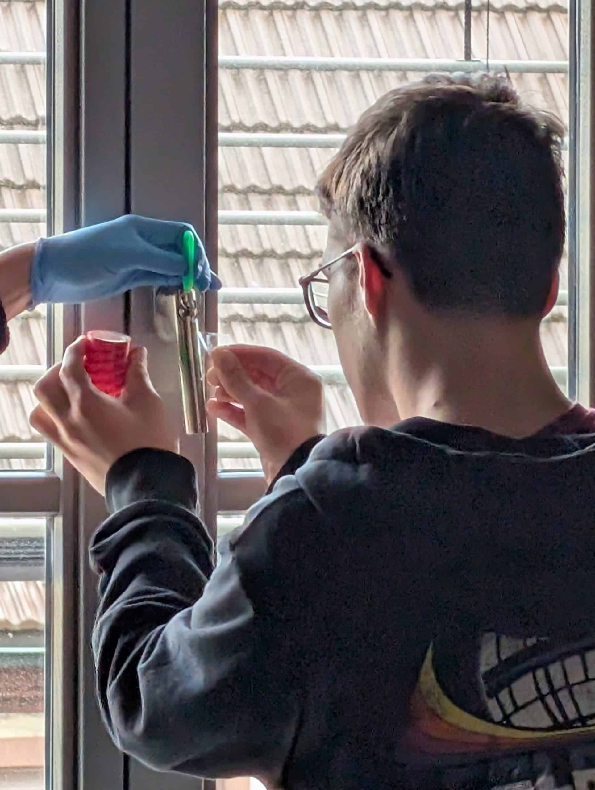 Ein Schüler nimmt mithilfe eines Tesafilms einen Fingerabdruck von einem Metallstück.