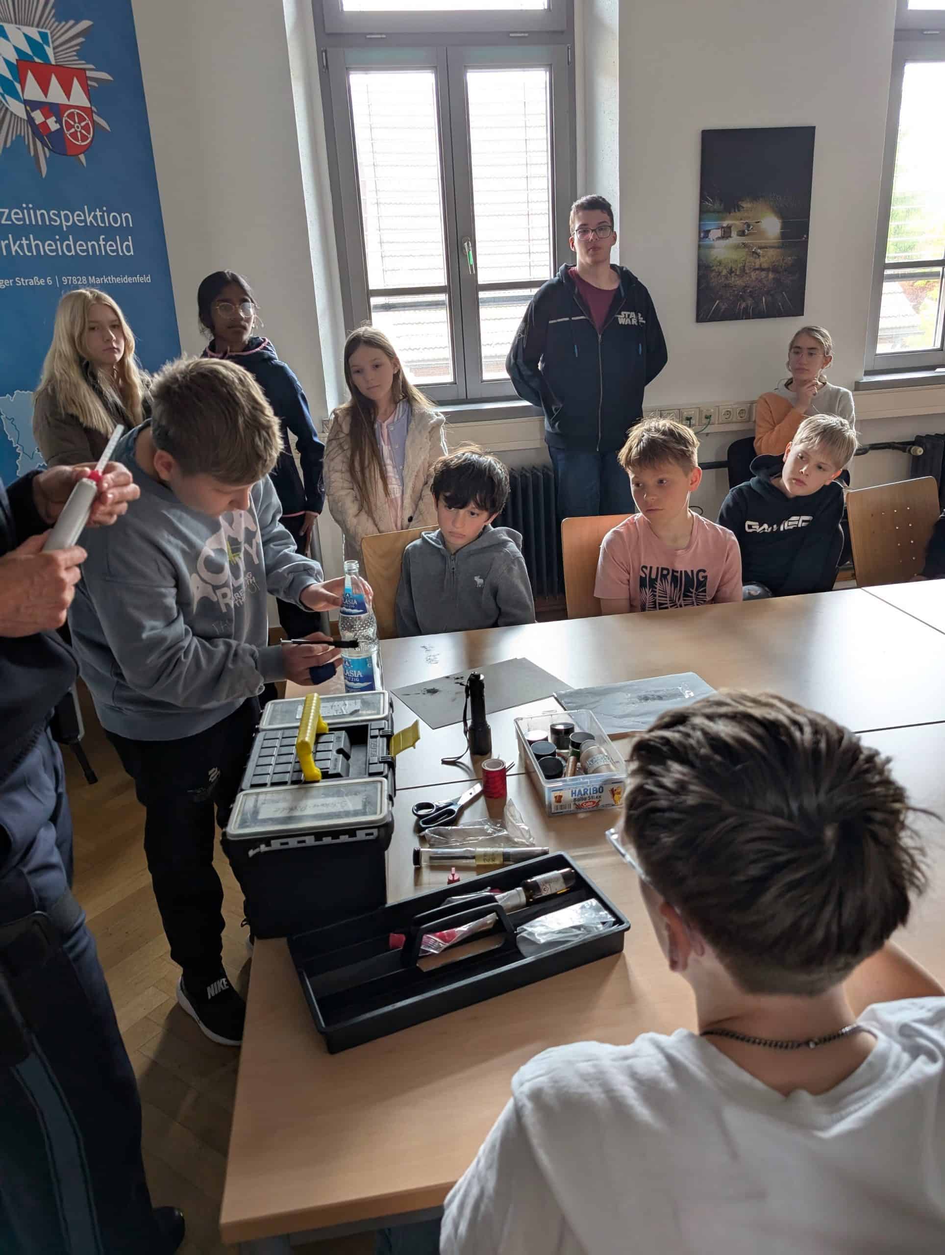 Ein Schüler sitzt an einem Tisch und probiert das Fingerabdruckpulver aus, das man bei der Spurensicherung verwendet.