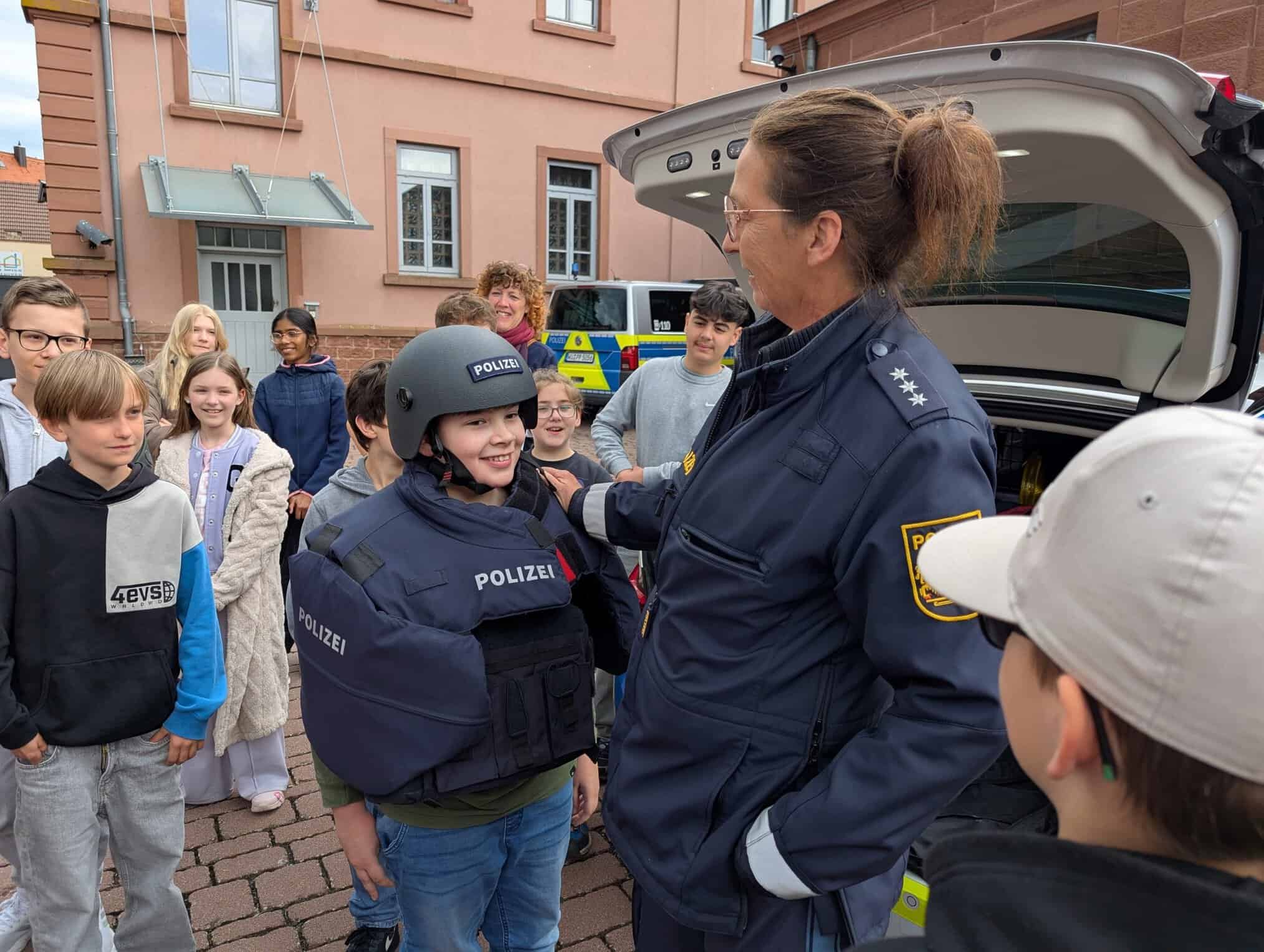 Ein Schüler steht in voller Montur mit Polizeihelm und Schutzweste neben einer Polizistin.
