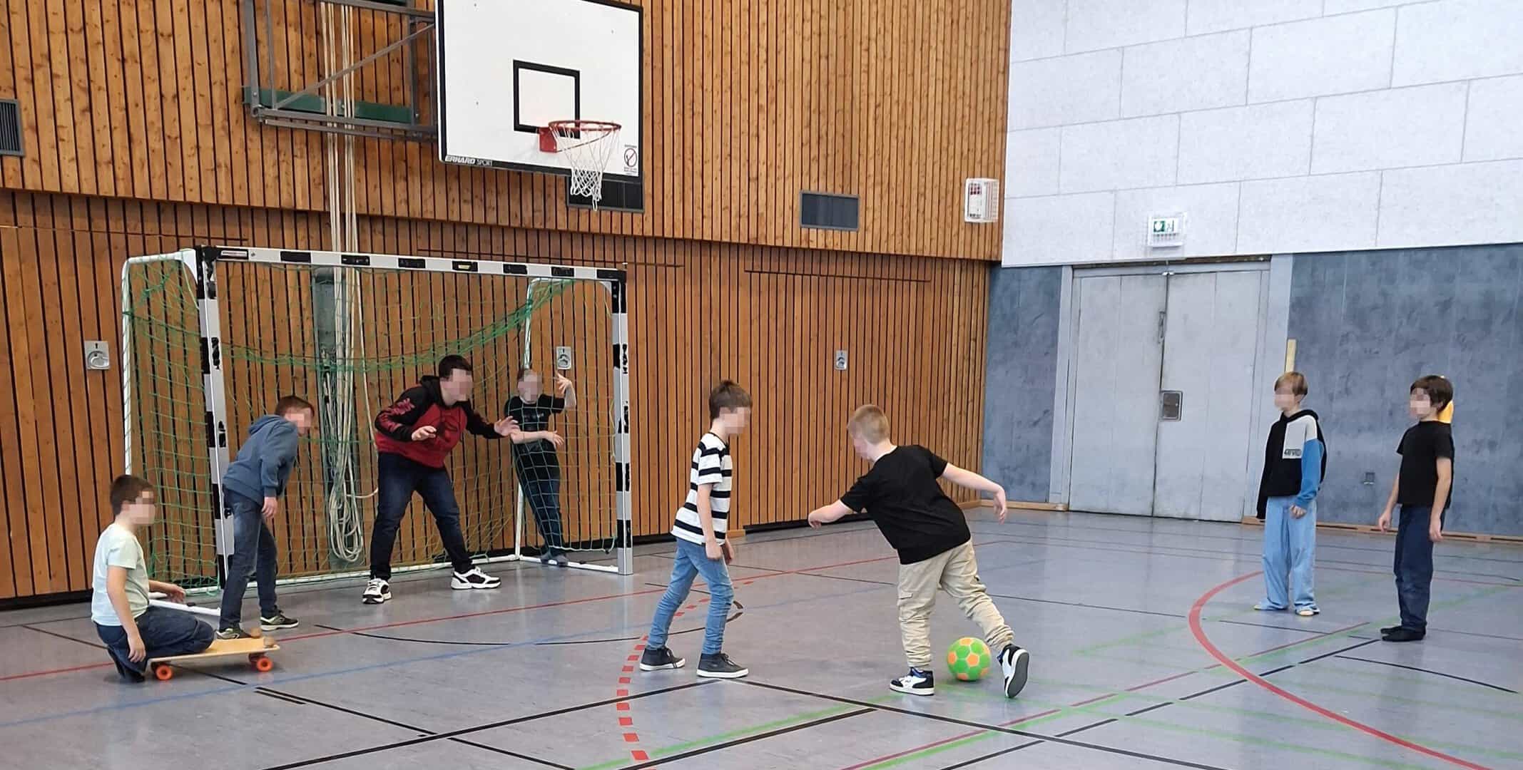 Kinder spielen in der Turnhalle Fußball.