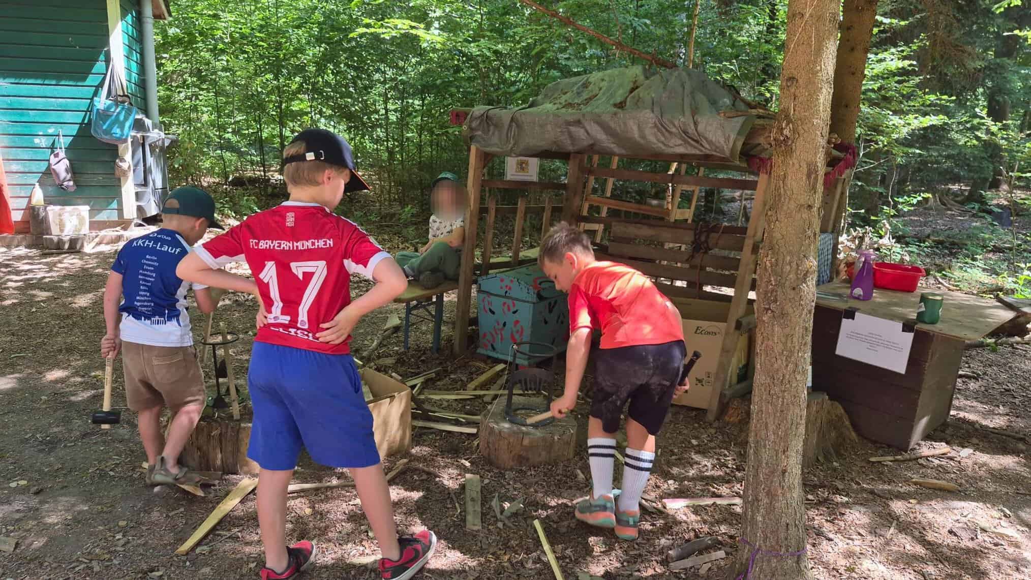 Kinder können an sicheren Holspaltvorrichtungen Holz spalten, indemsie mit ein Holzstück in eine Halterung einlegen und dann mit einem Gummihammer drauf hauen.
