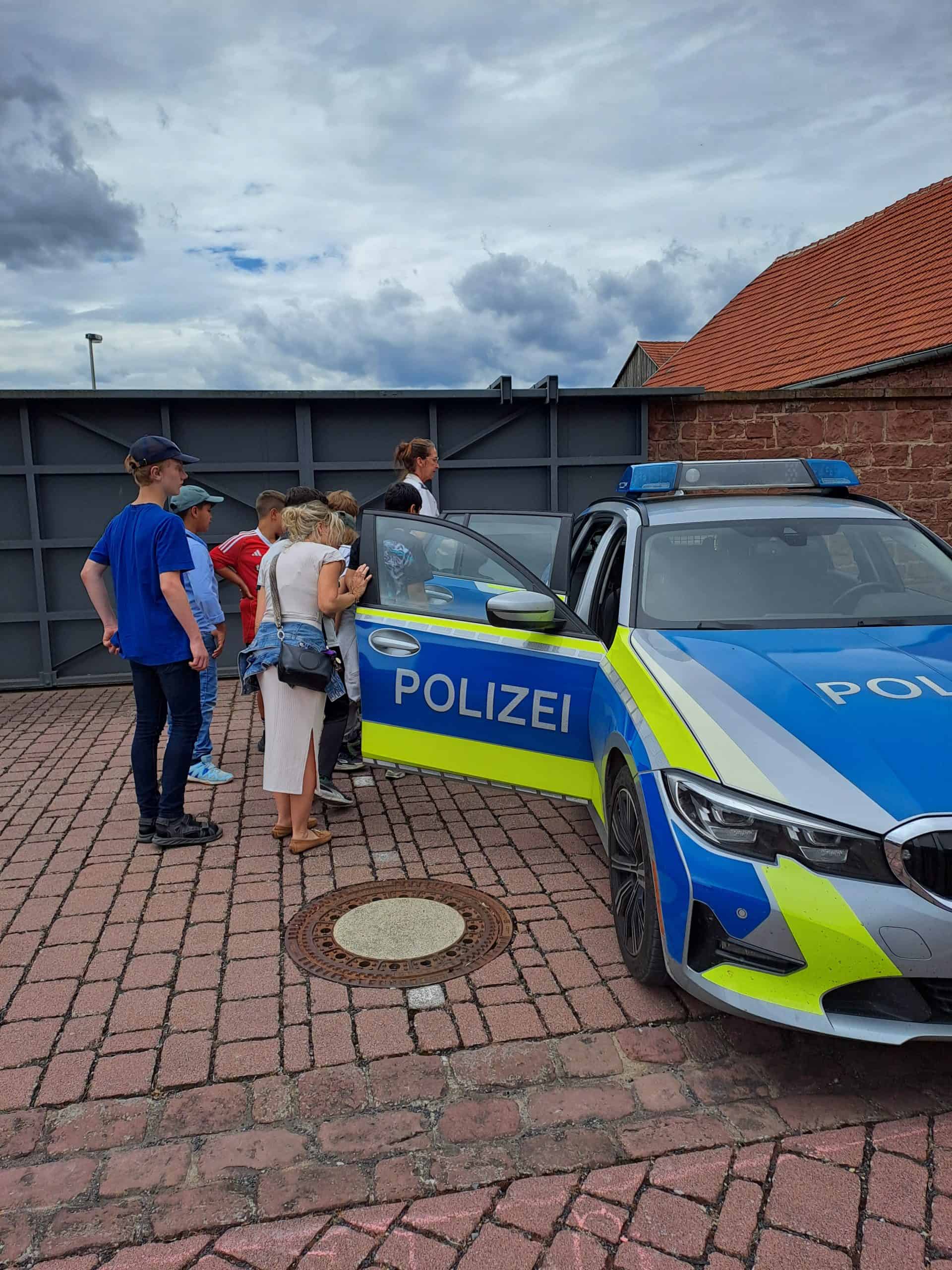 Die Schüler bekommen das Polizeiauto erklärt.