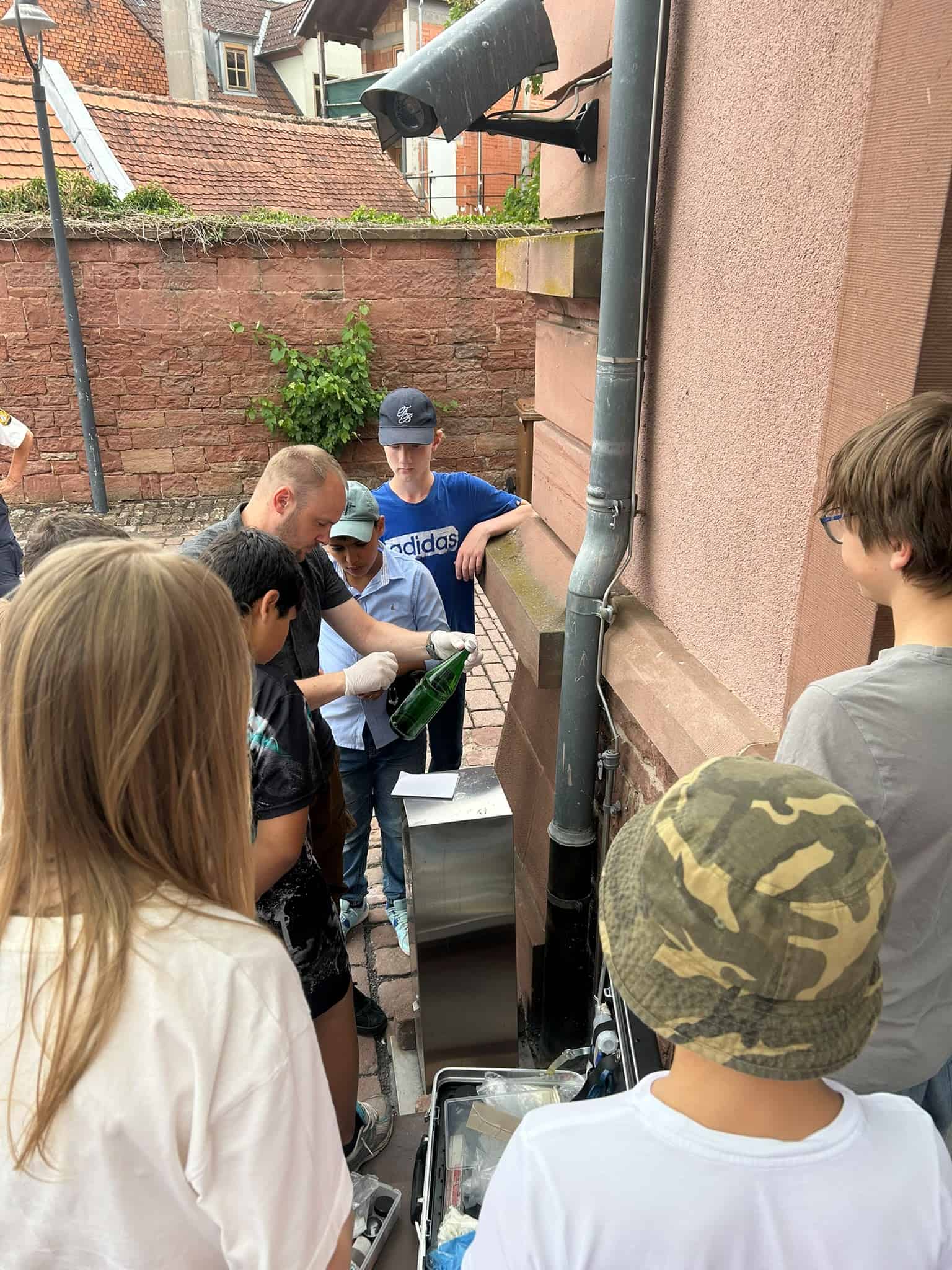 Ein Mann von der Polizei zeigt den Schülern, wie man einen Fingerabdruck von einer Glasflasche nimmt.