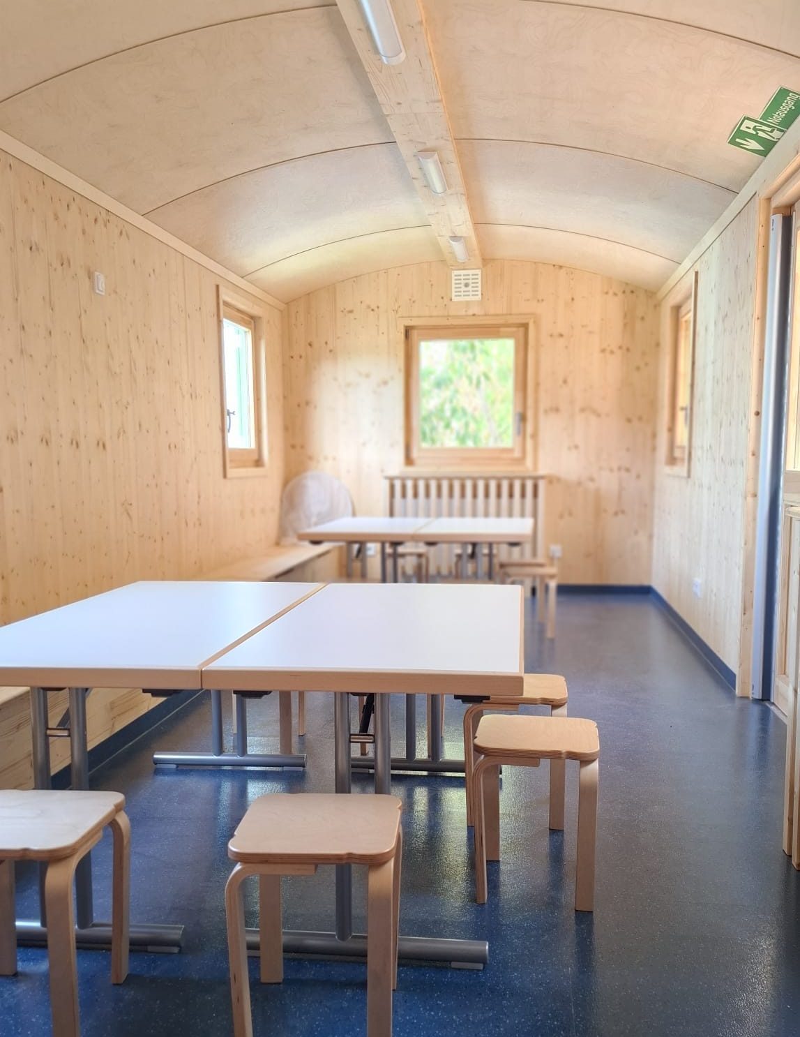 Der Bauwagen von Innen. Viel helles Holz und ein dunkelblauer Boden.
