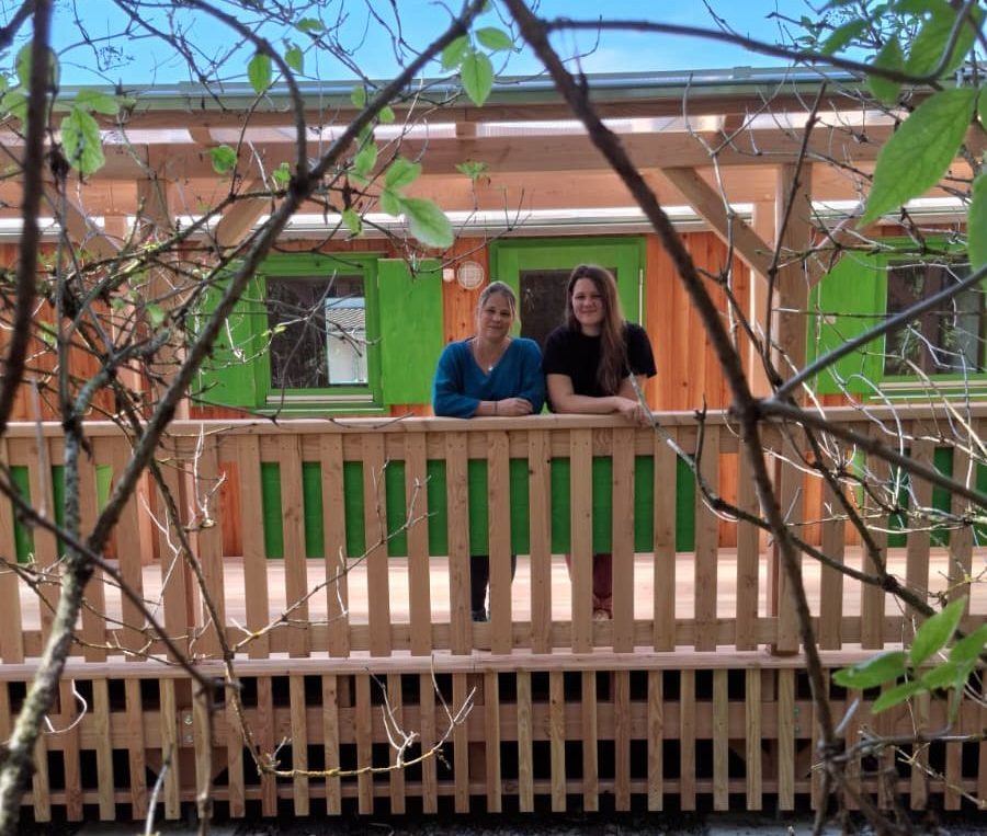 Das Team des Waldkindergarten steht auf der Terrasse des Bauwagen.