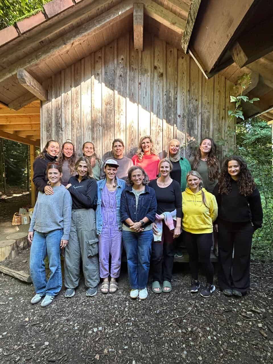 Das Team des Waldkindergarten Lindau steht vor einer Holzhütte im Wald